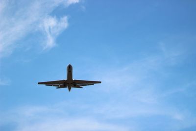 Low angle view of airplane against blue sky