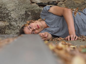 Portrait of man lying down by rock during autumn