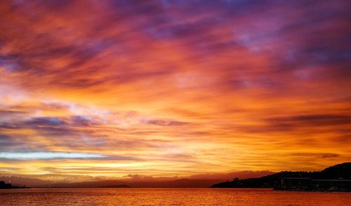 Scenic view of sea against cloudy sky during sunset