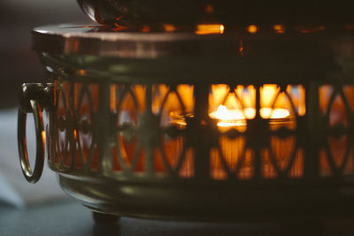 Illuminated candle in metallic lantern on table