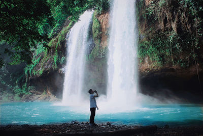 Man standing by waterfall in forest