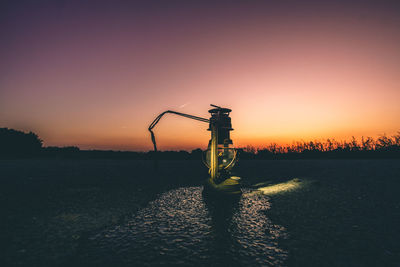 Lifeguard tower on field against clear sky during sunset