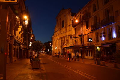 Illuminated street amidst buildings in city at night