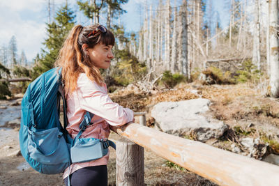 A young girl with a hiking backpack on her back leaned on the railing and is resting. 