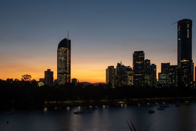 Modern buildings in city against sky during sunset