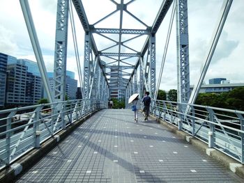 Rear view of man walking on footbridge