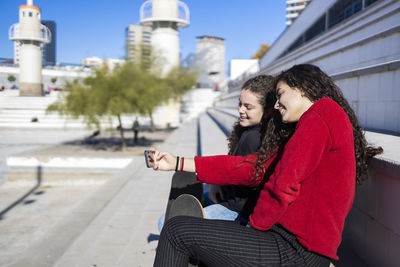 Girls taking selfie while sitting outdoors
