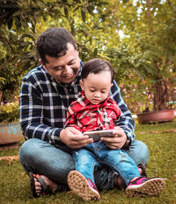 Father and son sitting on man looking at camera