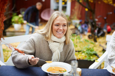 Happy female with vegetarian soup sitting by table at yard