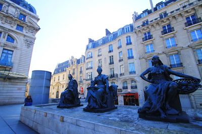 Statue by historic building against sky in city