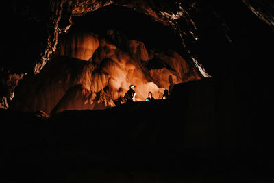 Silhouette people on rock in cave