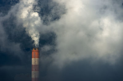 Low angle view of smoke emitting from chimney against sky