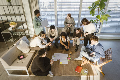 High angle view of multiracial male and female entrepreneurs discussing business strategy in meeting at creative office