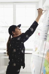 Businesswoman writing on whiteboard in creative office