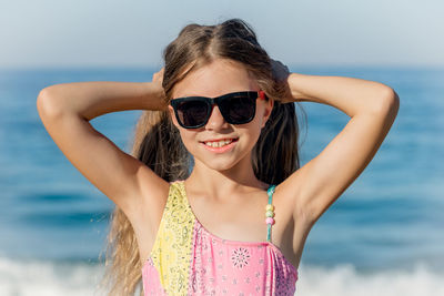 Cheerful girl in a swimsuit holds her hair with her hands at the resort.
