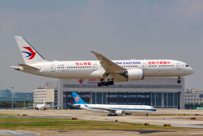 Airplane flying over airport runway against sky