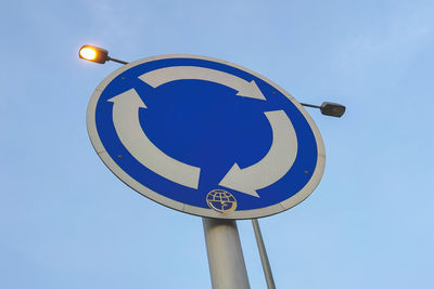 Low angle view of road sign against clear blue sky