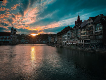 Buildings by river against sky during sunset over  lake of luzern