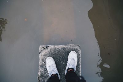 Low section of person standing next to lake