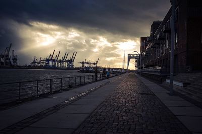 Sidewalk by sea against sky during sunset