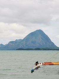 Man in boat on sea against mountains