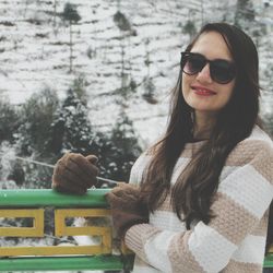 Portrait of young woman wearing sunglasses standing outdoors during winter