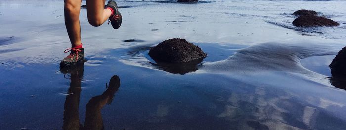 Low section of woman running in sea