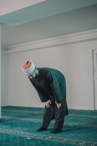 Side view of young man standing against wall