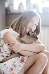 Portrait of blondie girl with burmese cat at home
