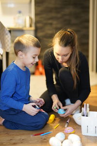 Mother and son making easter eggs on floor at home