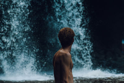 Rear view of shirtless man looking at sea