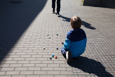 Rear view of boy looking at man walking on footpath