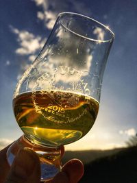 Close-up of hand holding drink against sky