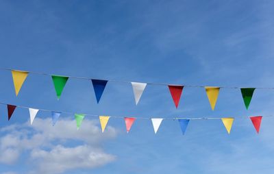 Low angle view of colorful flags against blue sky