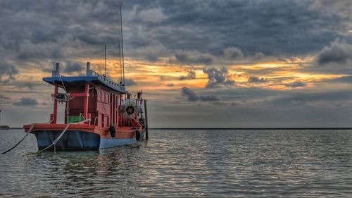 Fishing boat in sea against sky during sunset