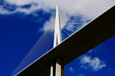 Low angle view of suspension bridge against blue sky