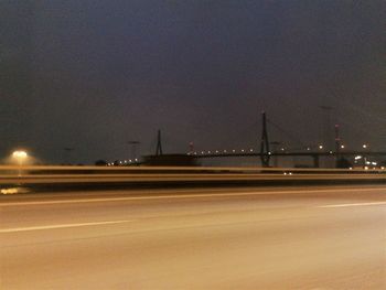 Road by bridge against sky at night