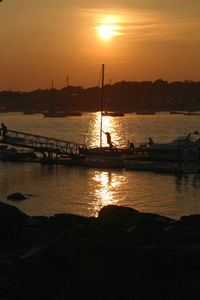 Silhouette sailboats in sea against sky during sunset