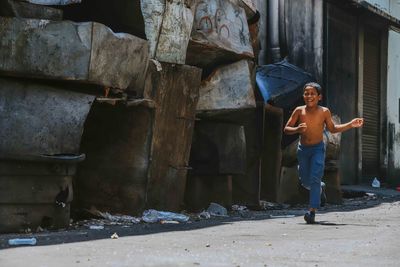 Full length of shirtless boy running by abandoned metal