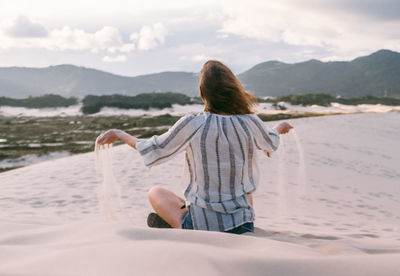 Rear view of woman on beach against sky