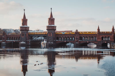 Bridge over river in city against sky