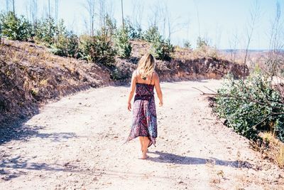 Full length rear view of woman walking on road