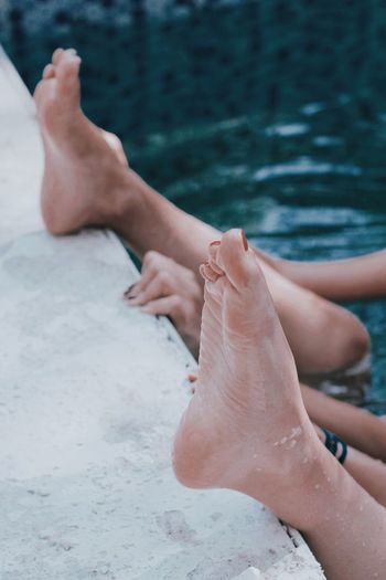 LOW SECTION OF WOMAN RELAXING ON WATER AT SHORE