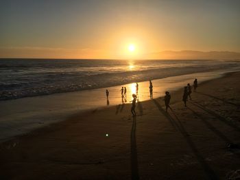 Silhouette people at beach during sunset