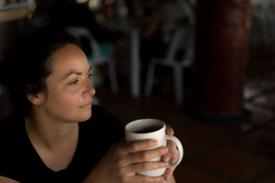 Thoughtful woman looking away while holding coffee cup