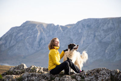 Dogs sitting on rock against mountains