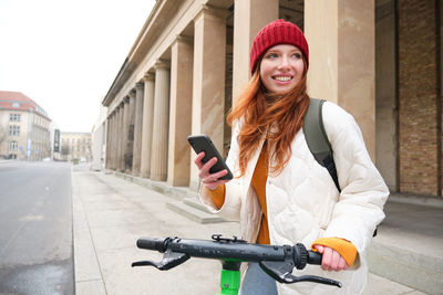 Portrait of young woman standing in city