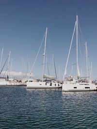 Sailboats moored at harbor against clear blue sky