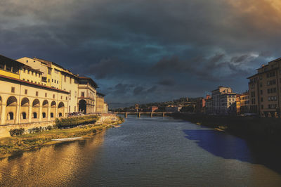 Buildings by river against sky in city