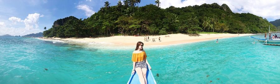 Rear view of woman standing on beach against sky